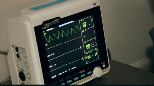 A close-up clinical monitor showing a live green patient waveform